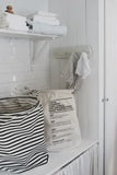 Eco-friendly laundry bag with care instructions, styled in a bright, minimalist laundry room