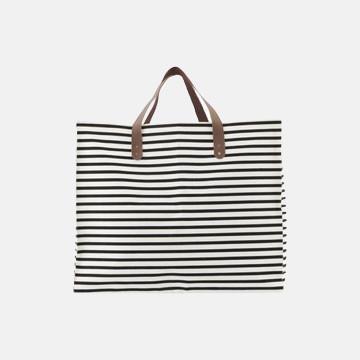 Black and white striped canvas tote bag with brown leather handles, ideal for luxury garment care transport